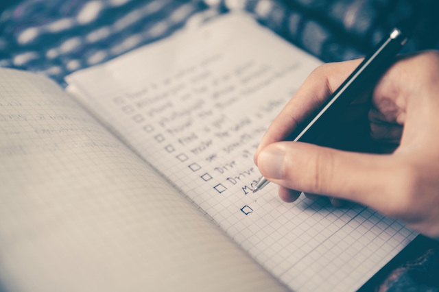 woman writing in notepad g a checklist